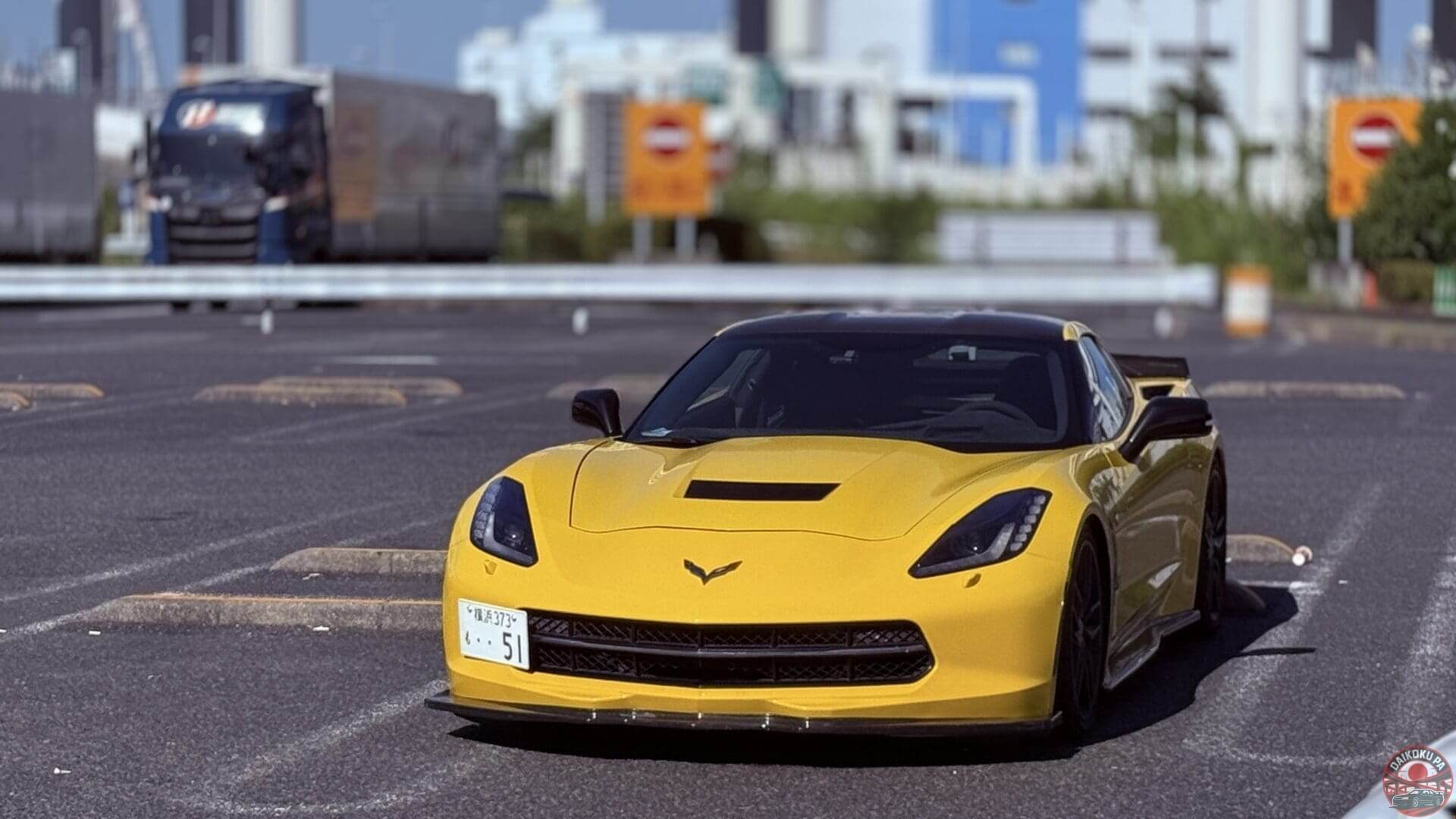 Yellow sports car parked near a road with a street sign in the background.
